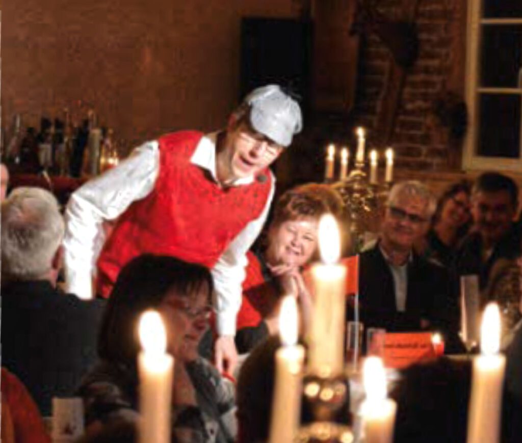 Schauspieler interagiert beim Krimidinner im Kerzenschein mit den Gästen.